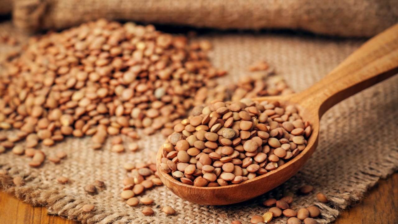 heap of lentils in wooden spoon