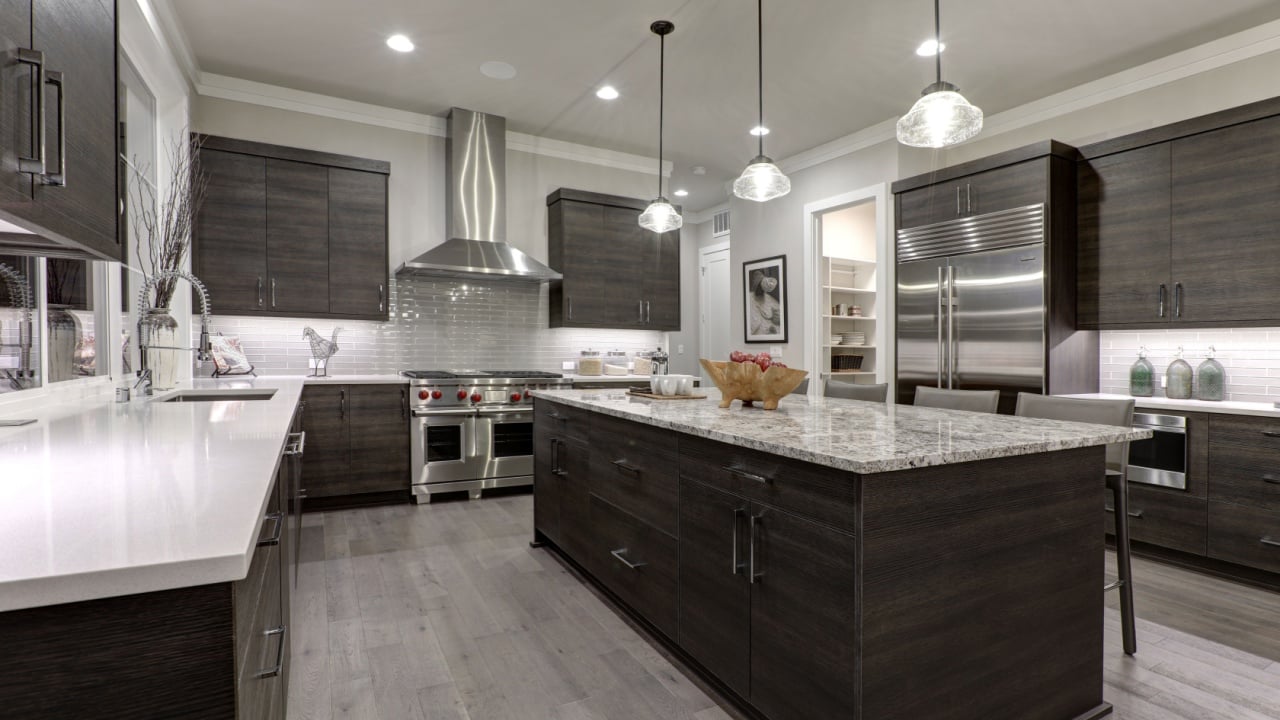 Modern gray kitchen features dark gray flat front cabinets paired with white quartz countertops and a glossy gray linear tile backsplash. Northwest, USA