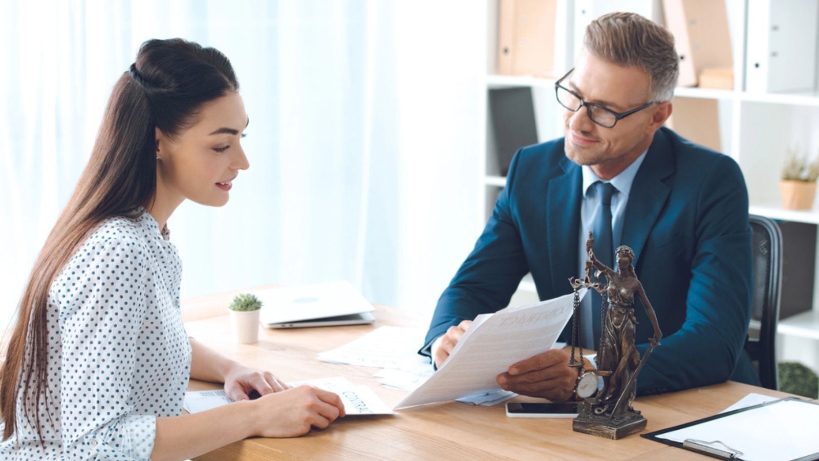 Smiling lawyer showing papers to happy client in office