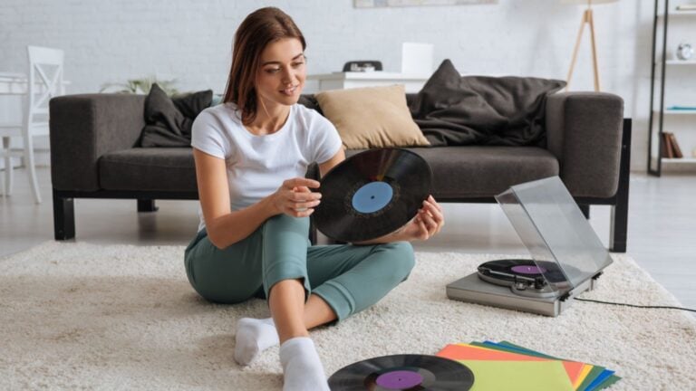 Smiling woman holding vinyl record while chilling at home