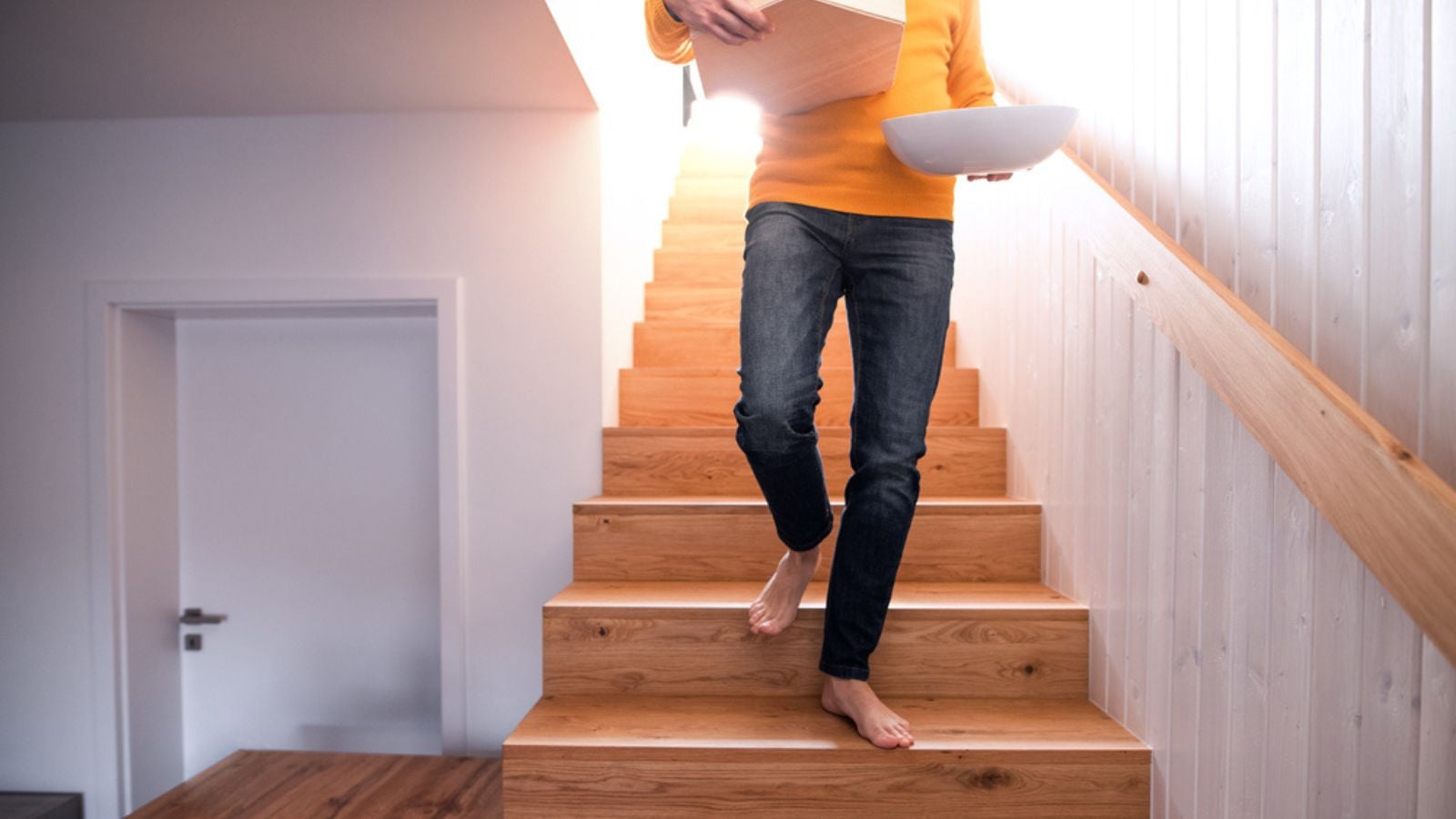 Unrecognizable man with boxes moving in new unfurnished house, walking