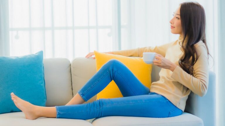 happy single woman drinking coffee on her couch in her living room