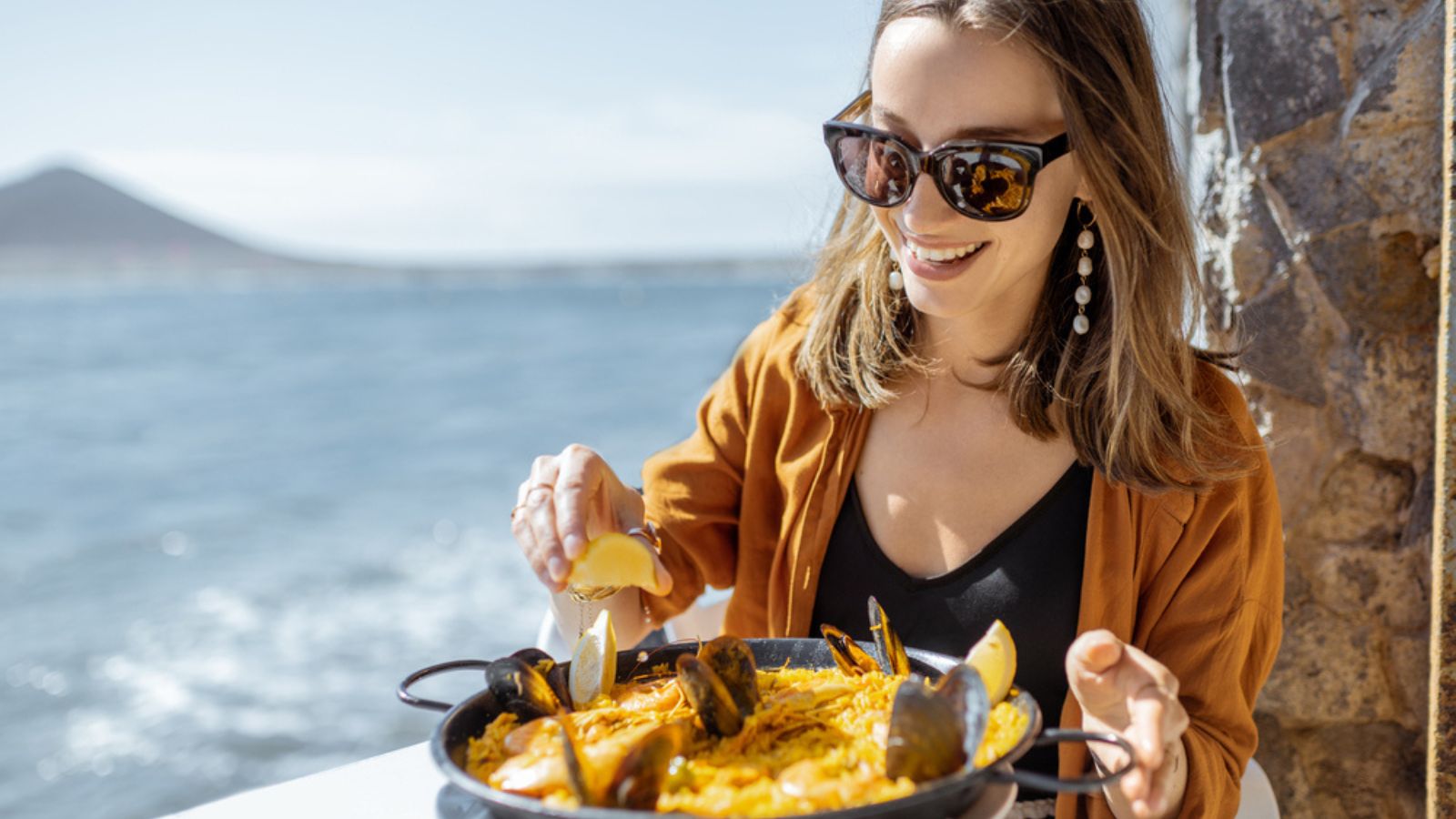 Woman eating paella sea food near the ocean