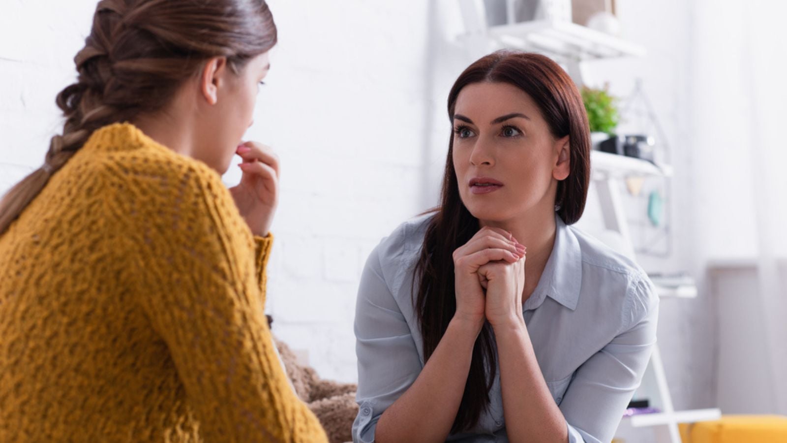 Worried mother looking at teenage daughter on blurred foreground