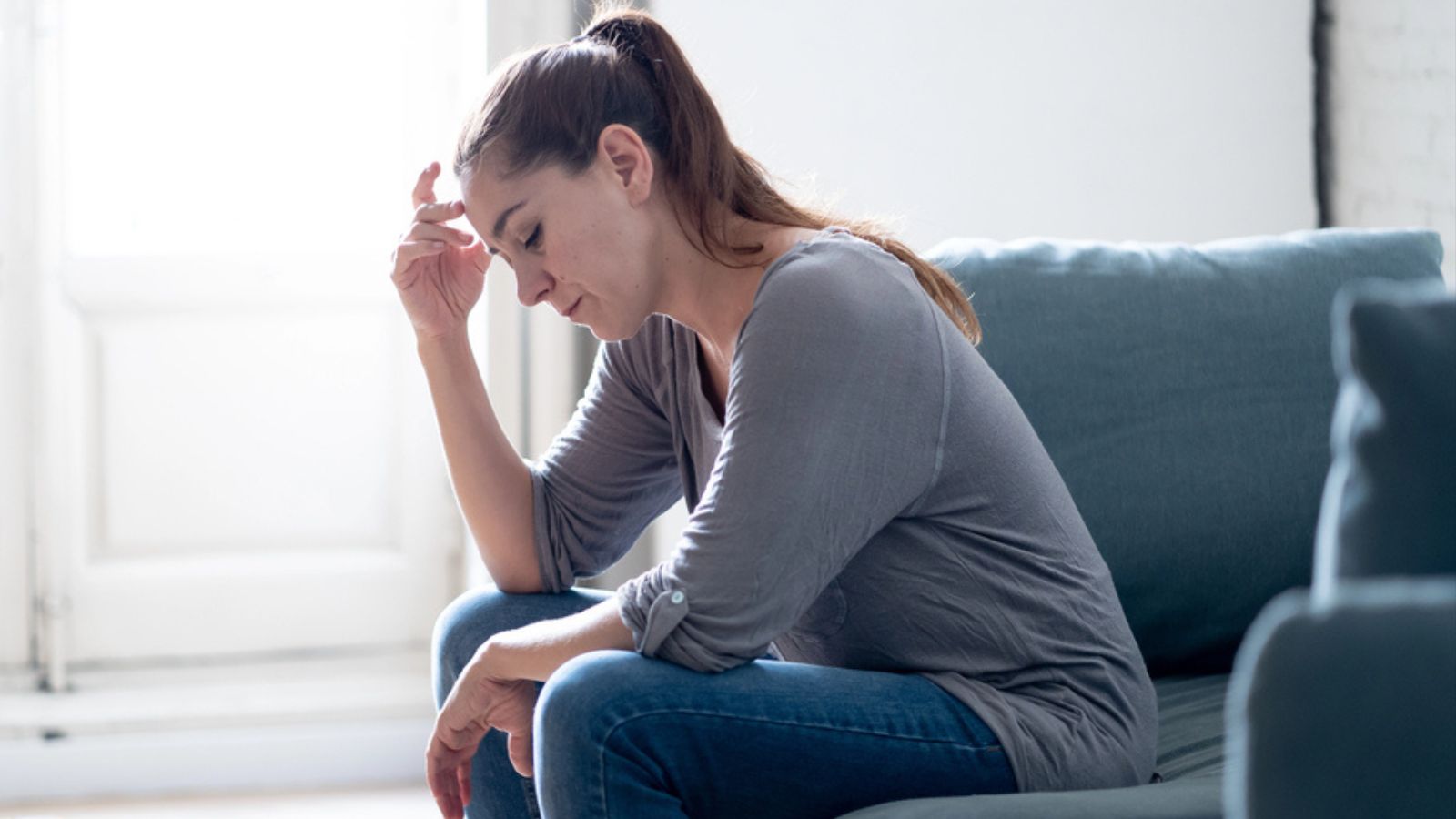 Young attractive latin woman lying at home living room couch feeling sad tired and worried suffering Depression
