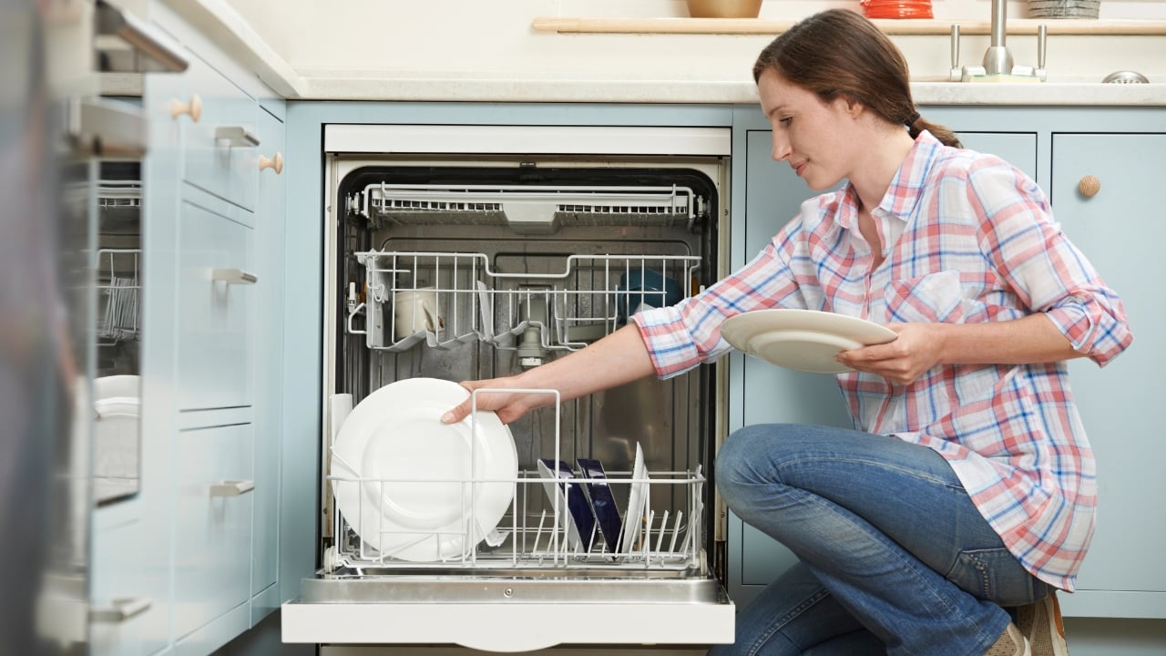 a woman loads a dishwasher
