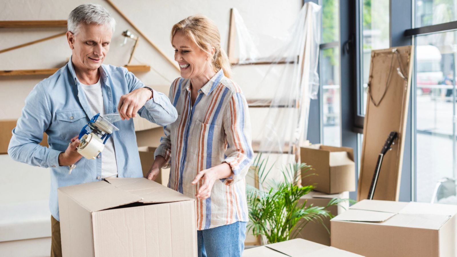 older retired married couple packing boxes moving new house