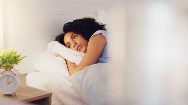 woman awake laying in bed insomnia can’t sleep dreaming