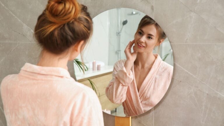 woman looking at herself in the mirror skincare bathroom getting ready