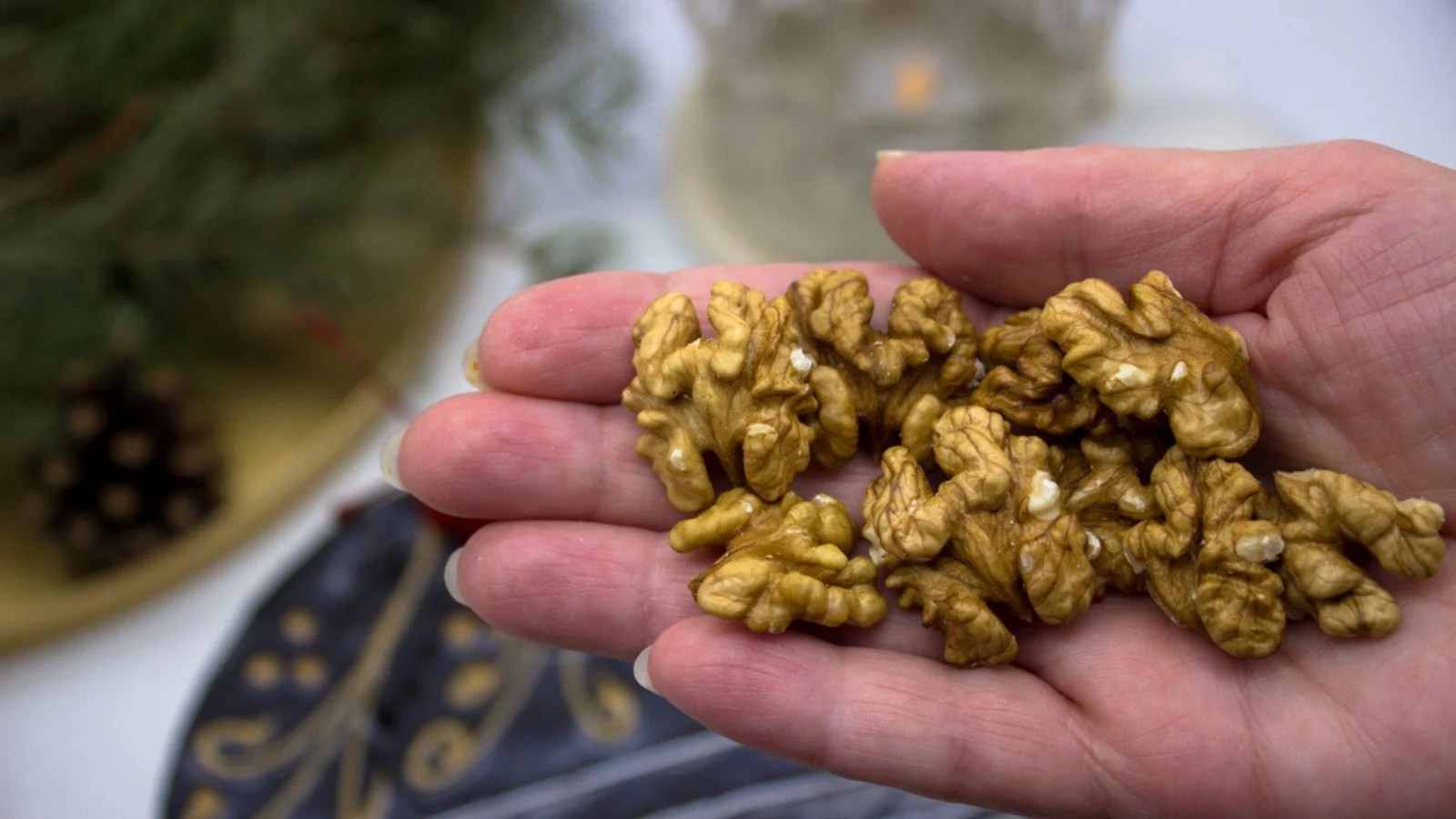 A hand that holds walnuts. In the background, a delicious chocolate
