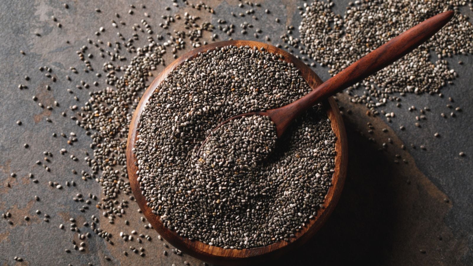 Chia seeds in wooden bowl with spoon on table