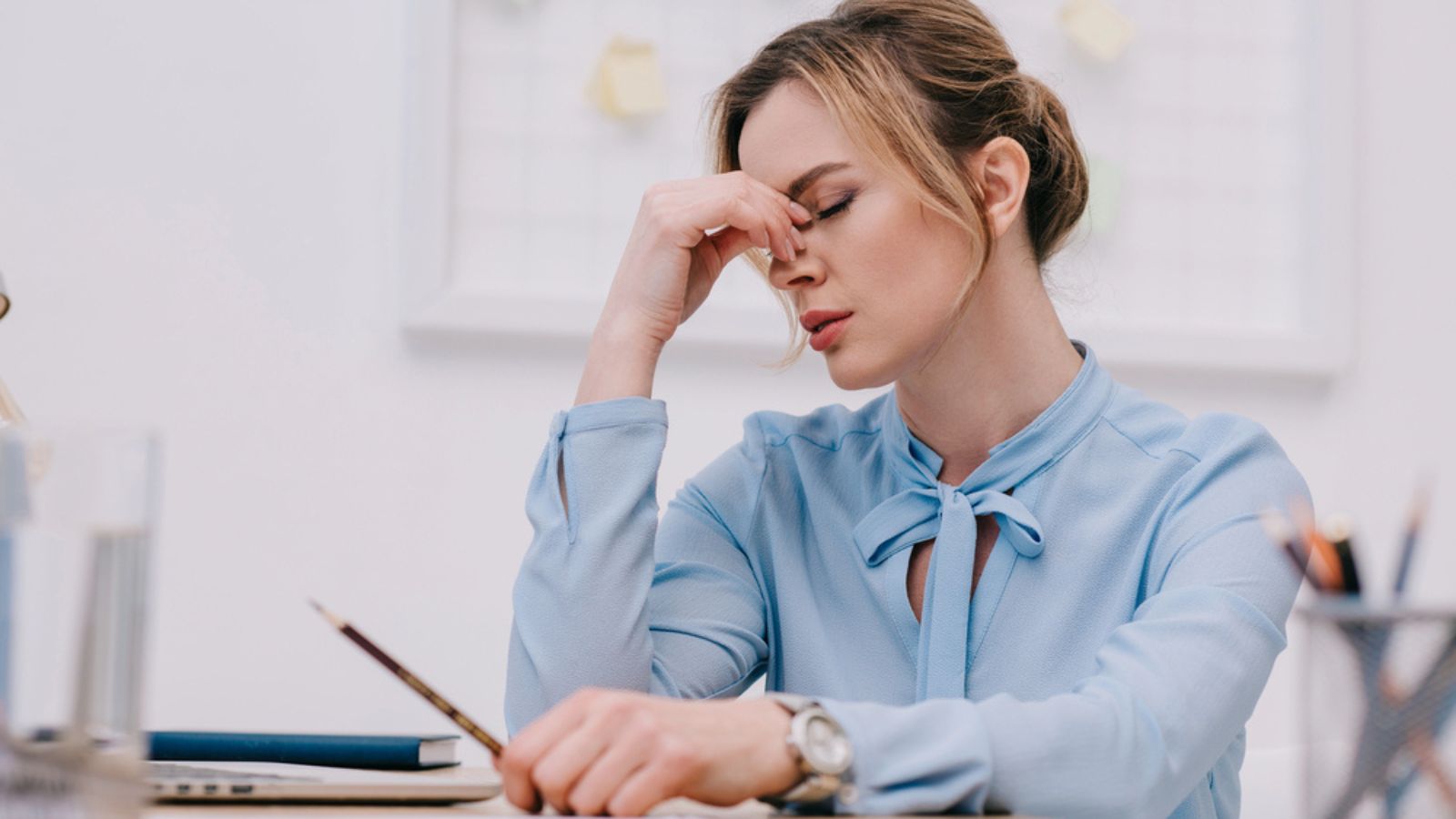 Exhausted adult businesswoman sitting at workplace in office