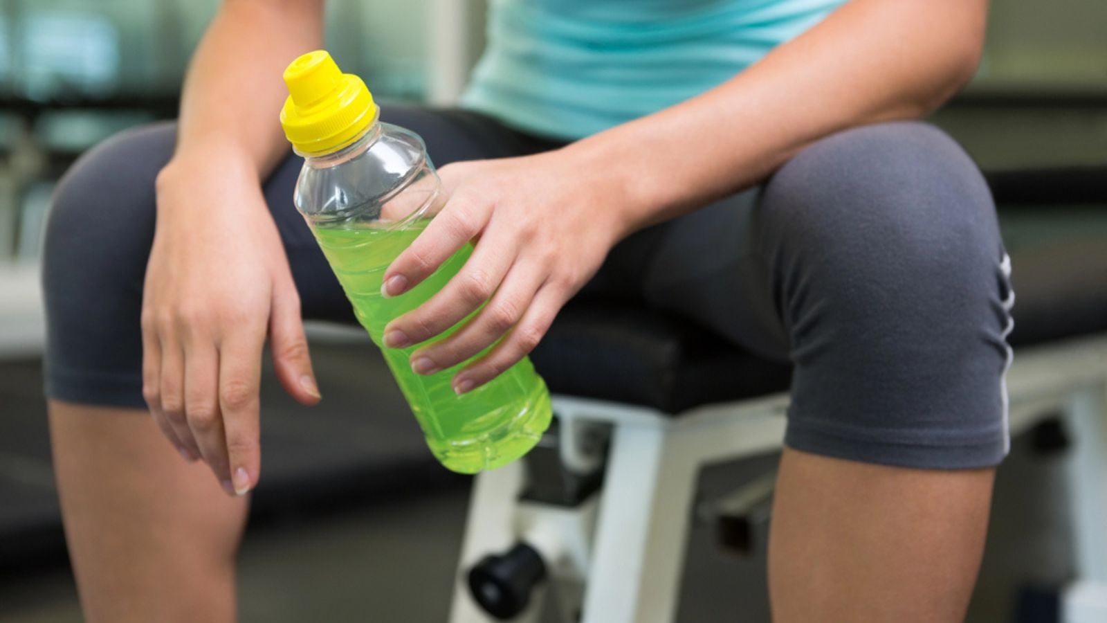 Fit woman sitting on bench holding energy drink