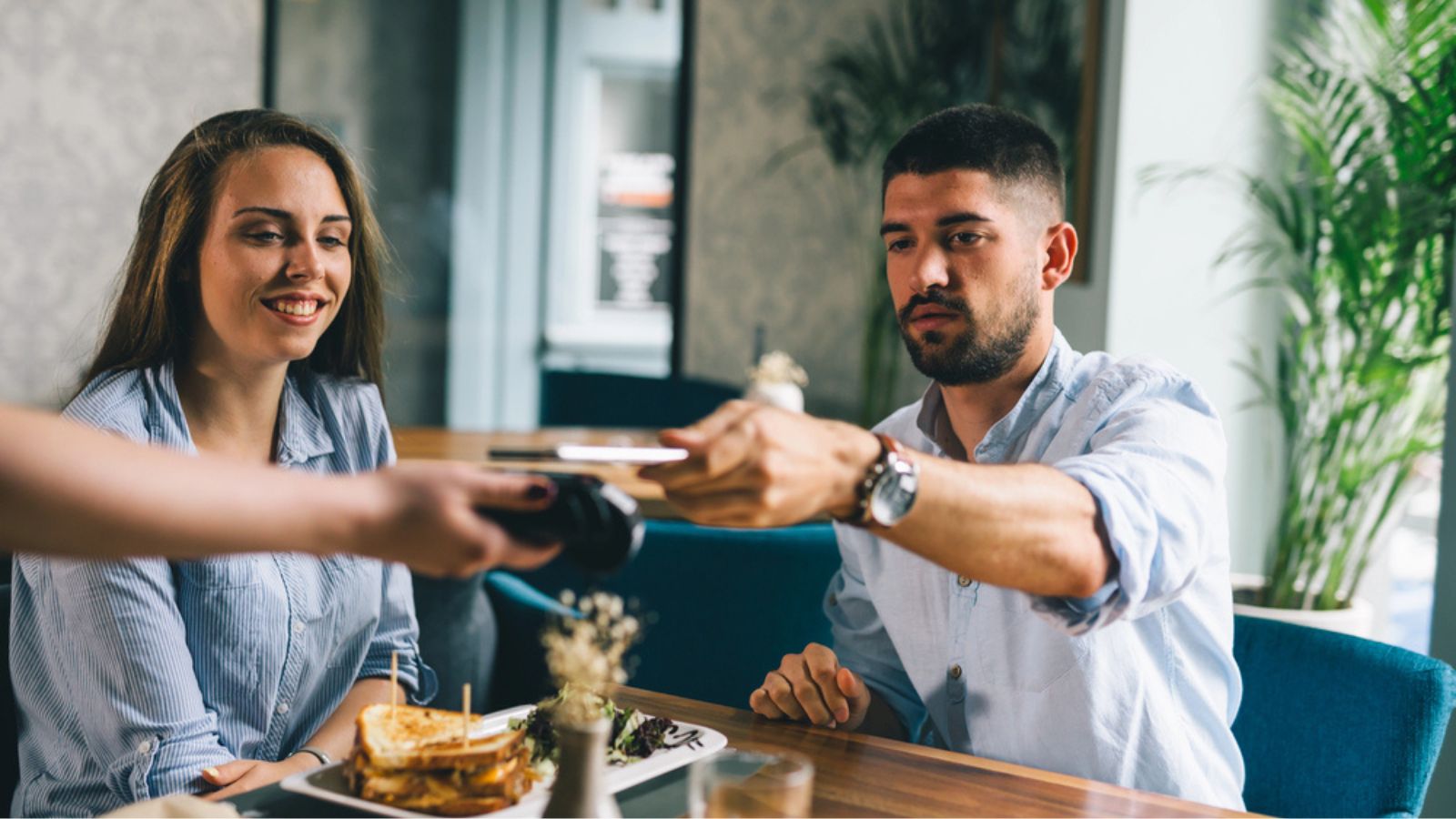 Man paying the bill in restaurant contactless with cellphone