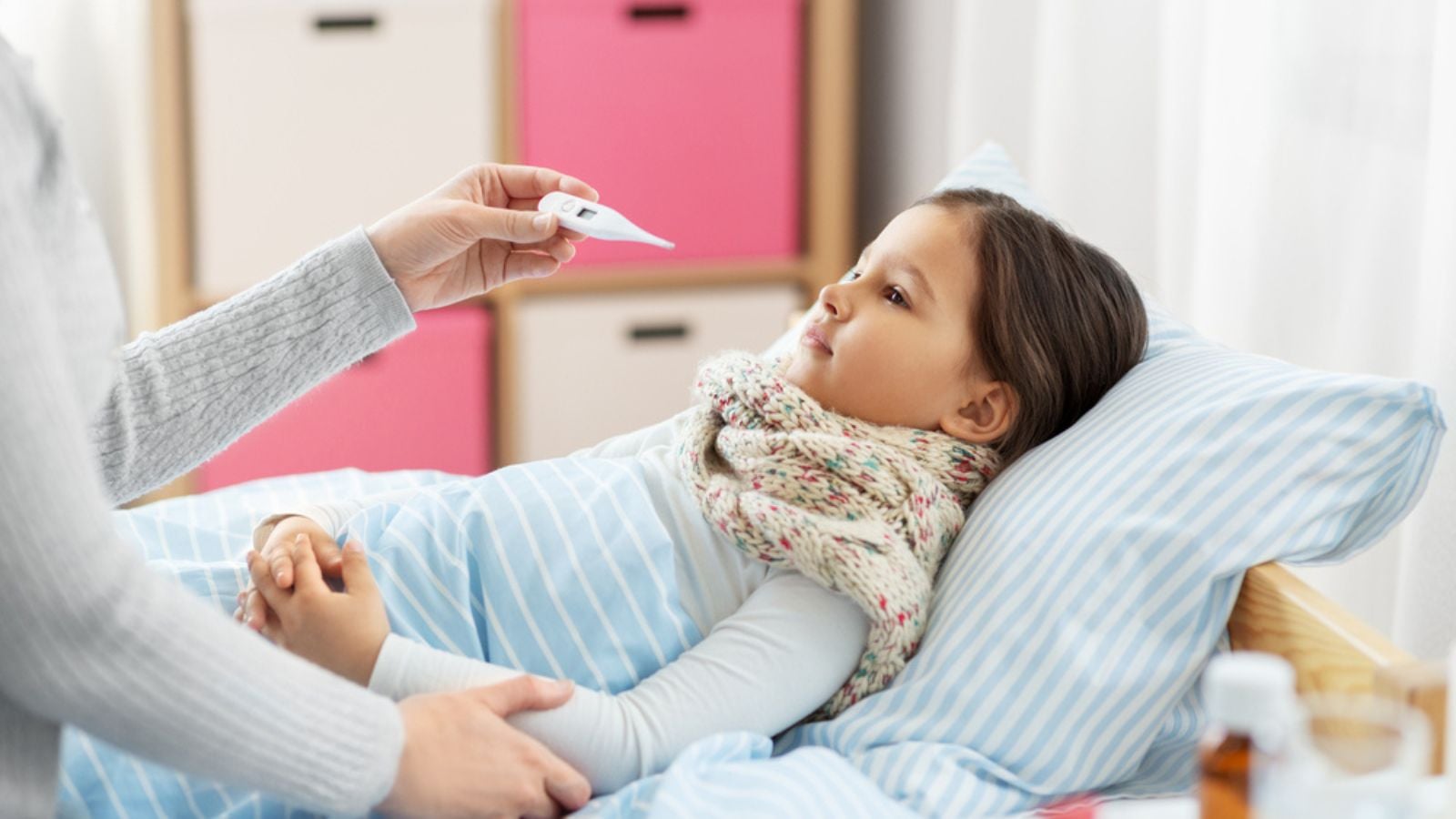 Mother measuring temperature of sick daughter
