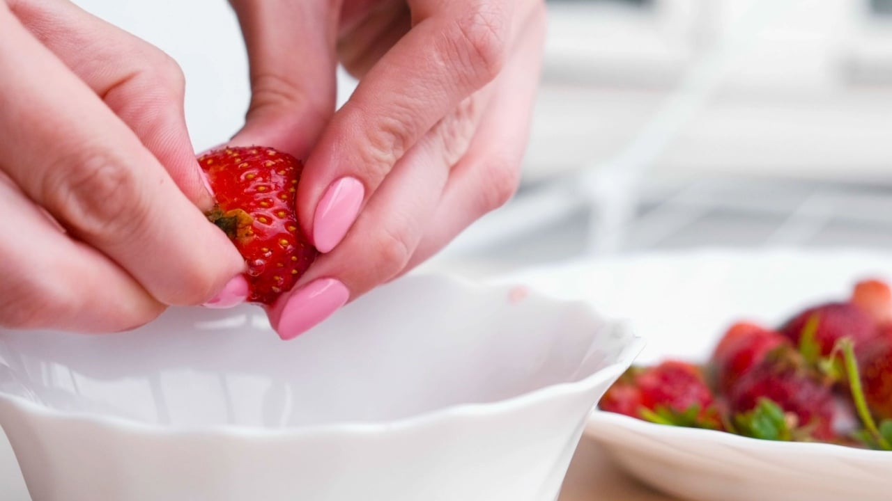 Woman cleans strawberries and puts it in a bowl. Close-up woman's hands.