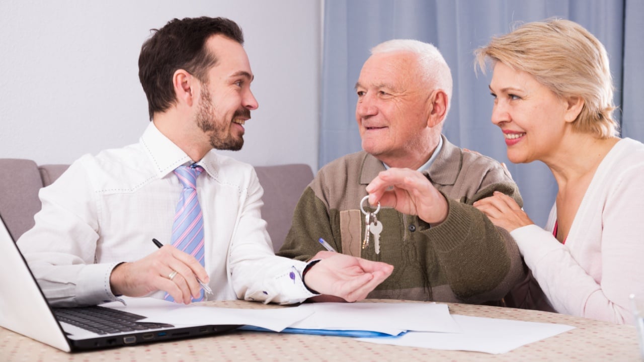 Aged couple signing papers to sell their house at home