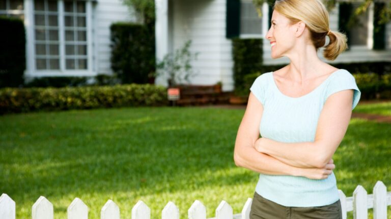 Woman standing by the garden fence outside her new home