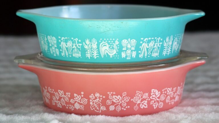 Two vintage milk-glass one-pint casserole dishes stacked on top of each other. One is aqua blue with an Amish pattern. One is pink with a gooseberry pattern.
