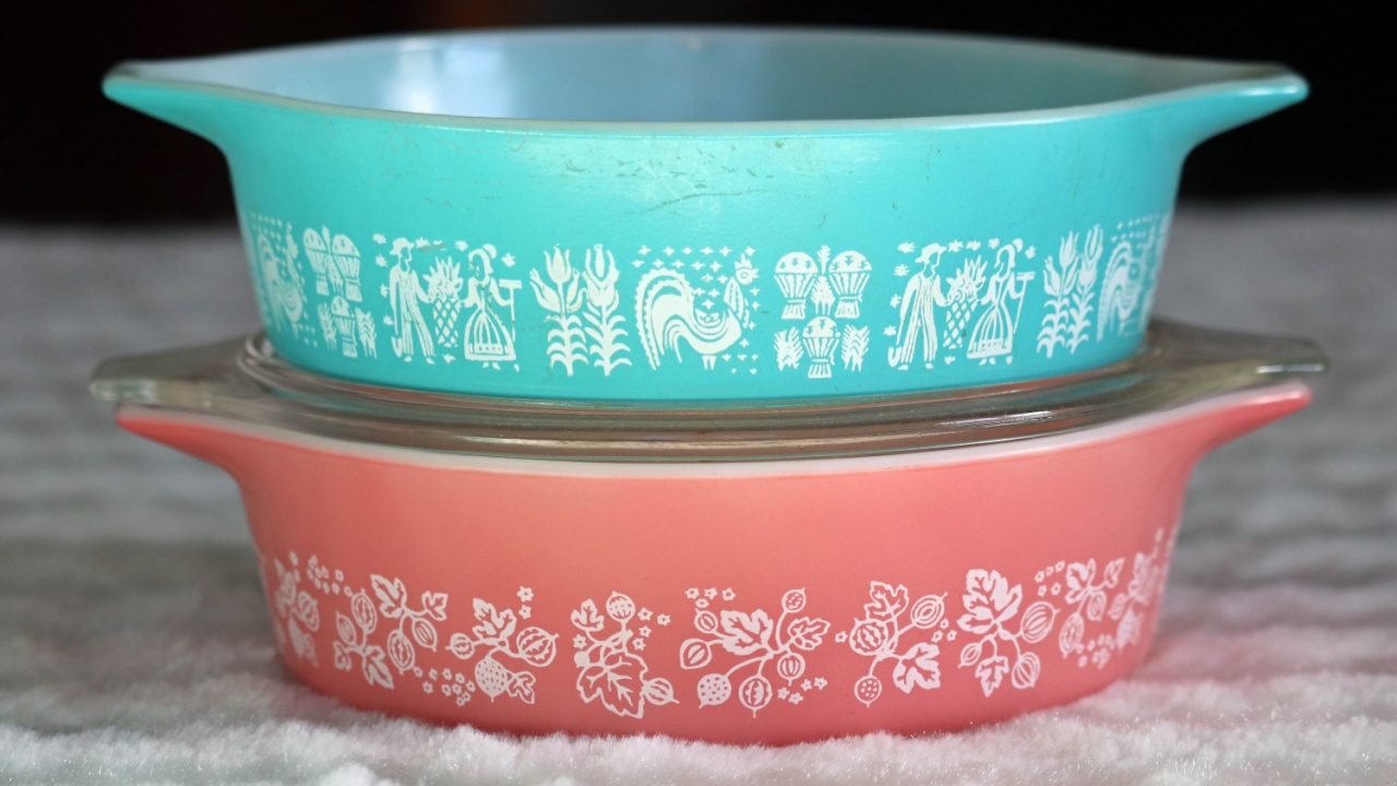 Two vintage milk-glass one-pint casserole dishes stacked on top of each other. One is aqua blue with an Amish pattern. One is pink with a gooseberry pattern.