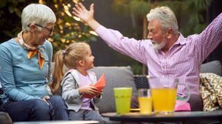 grandfather amusing his granddaughter, telling story with his arms spread, showing something big