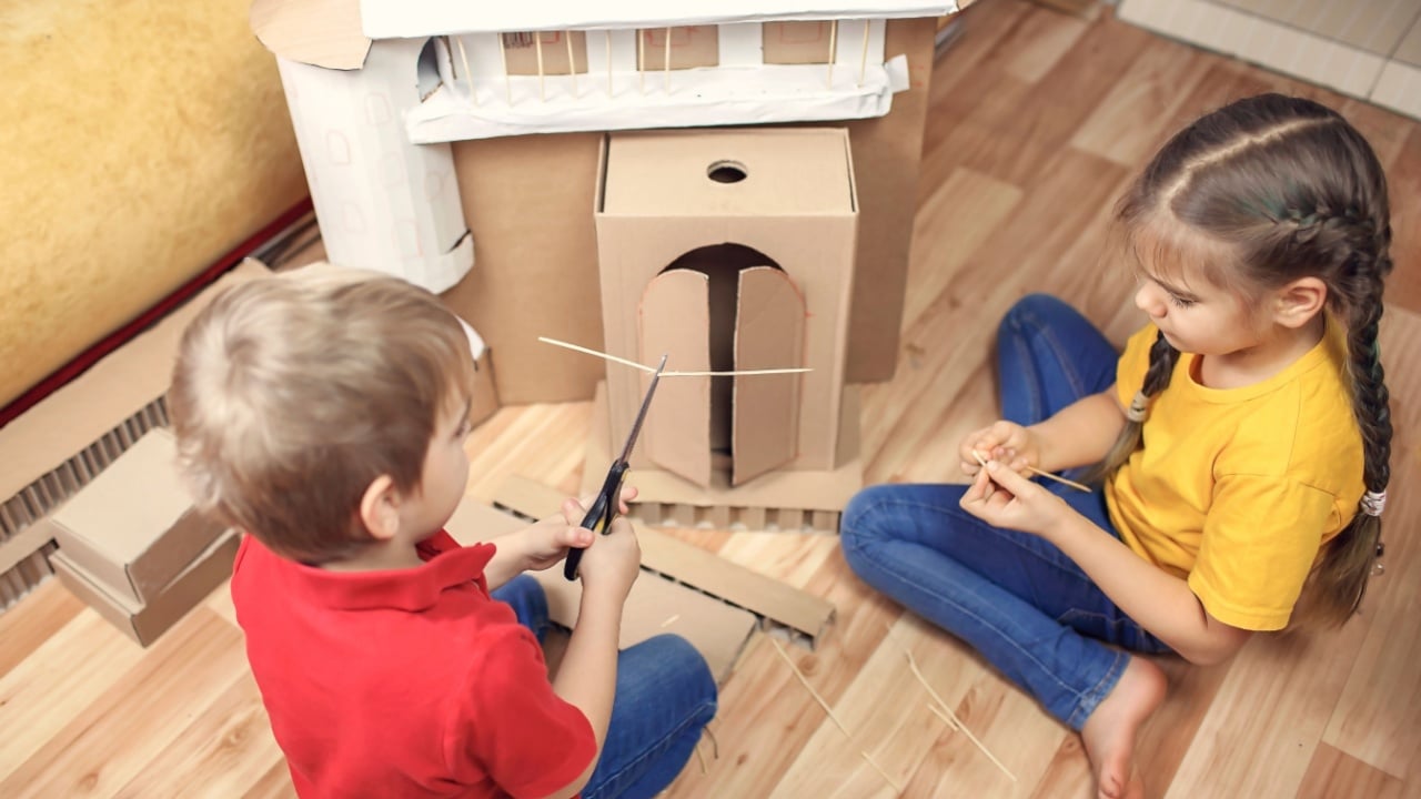 Zero waste home activity. Kids doing paper house with cardboard box after online delivery and playing together, creative idea for home isolation. Imagination skills and creatively thinking concept