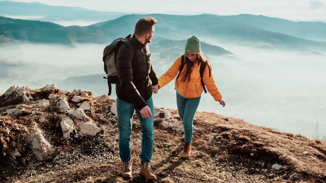 happy couple man and woman tourist at top of mountain during a hike in summer