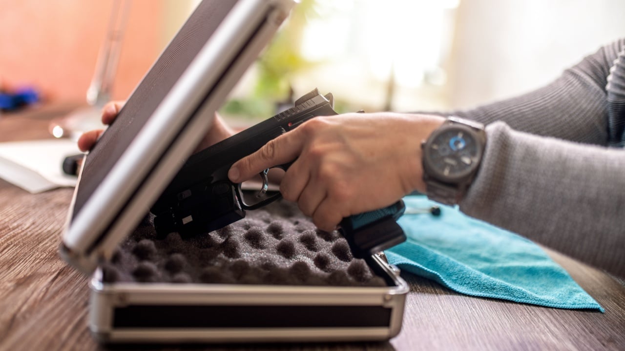 Man putting gun in safe box at home.
