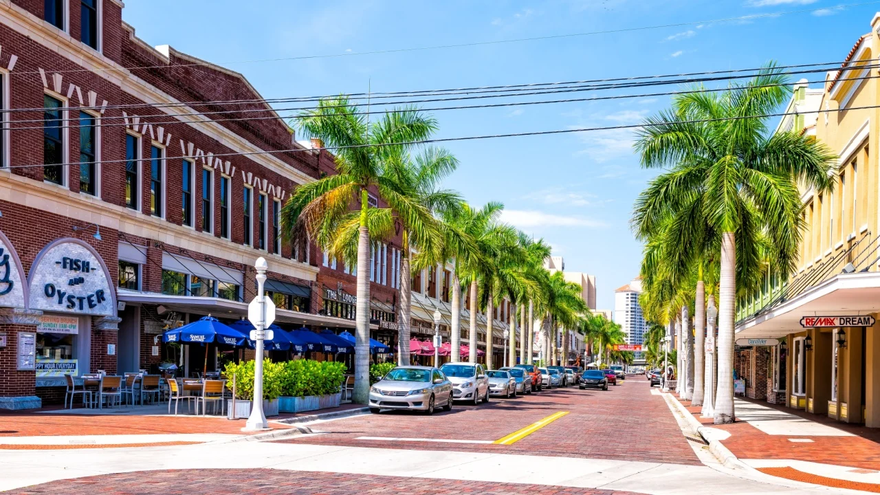 Fort Myers, USA - April 29, 2018: City town main street during sunny day in Florida gulf of mexico coast with shopping and restaurants row palm trees