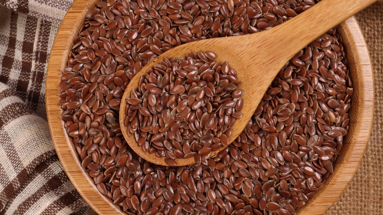 Flex seed flaxseed in wooden bowl spoon on jute fabric cloths top view