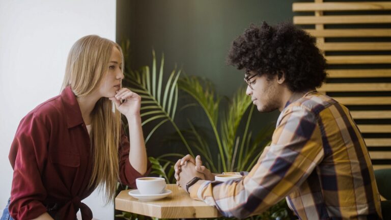 Upset girlfriend sitting in silence with boyfriend in cafe, relationship crisis, breakup