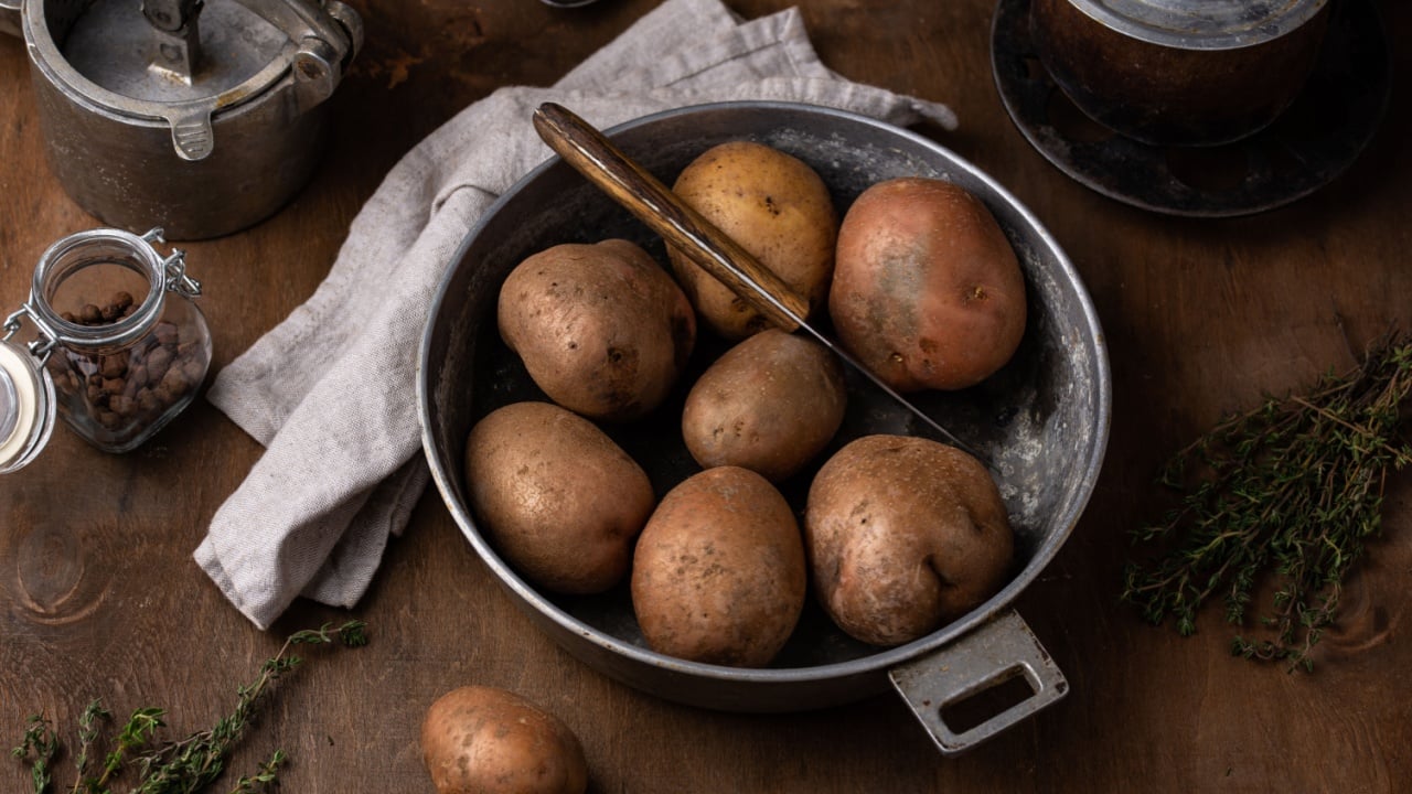 Raw uncooked potato in old vintage pot. Rustic kitchen background