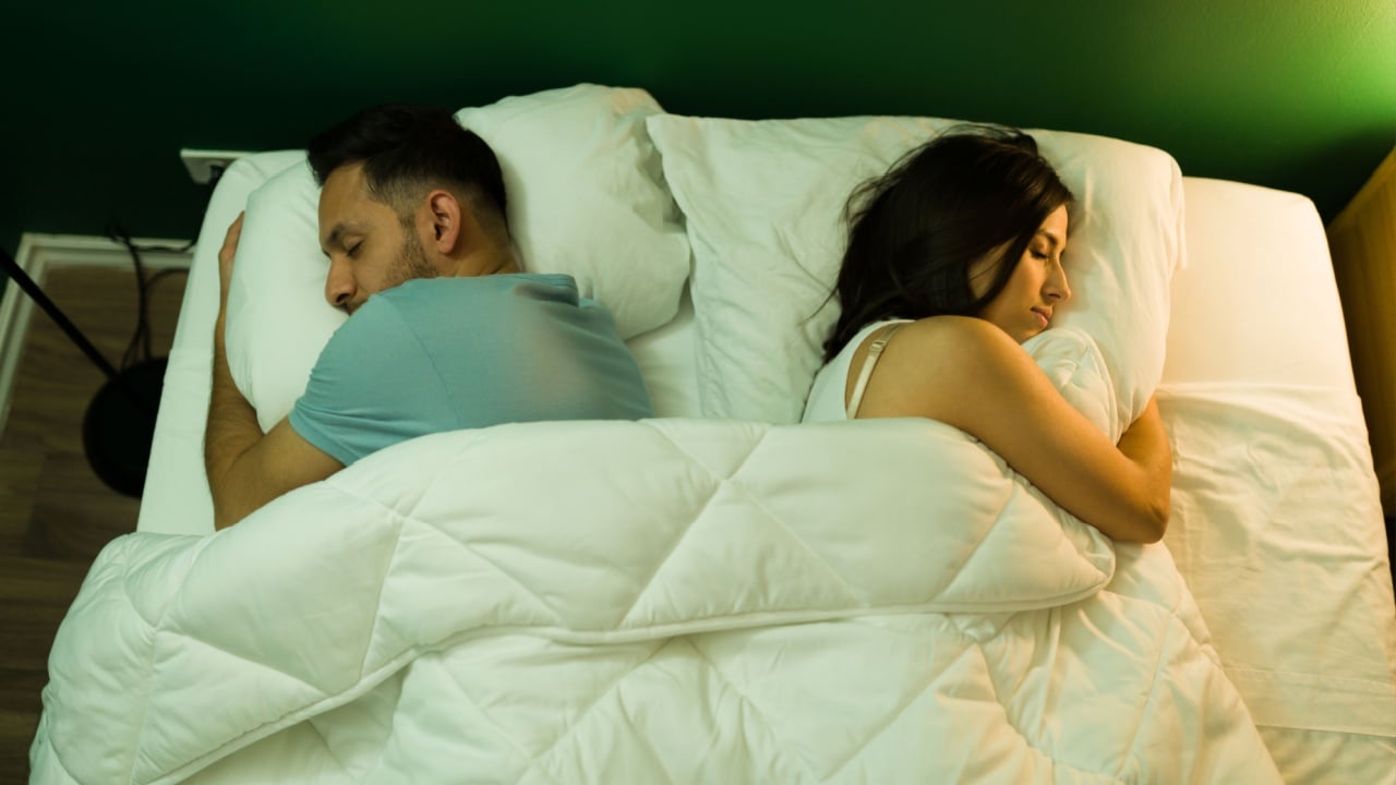 High angle of a young couple sleeping apart on the bed after a fight. Young woman and man resting on a comfy bed