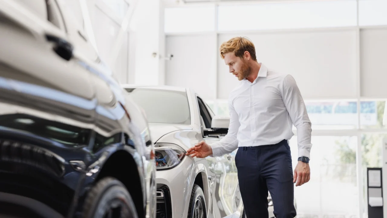 Man adult customer male buyer client wears classic suit white shirt chooses auto wants to buy new automobile touch check car in showroom vehicle salon dealership store motor show indoor.