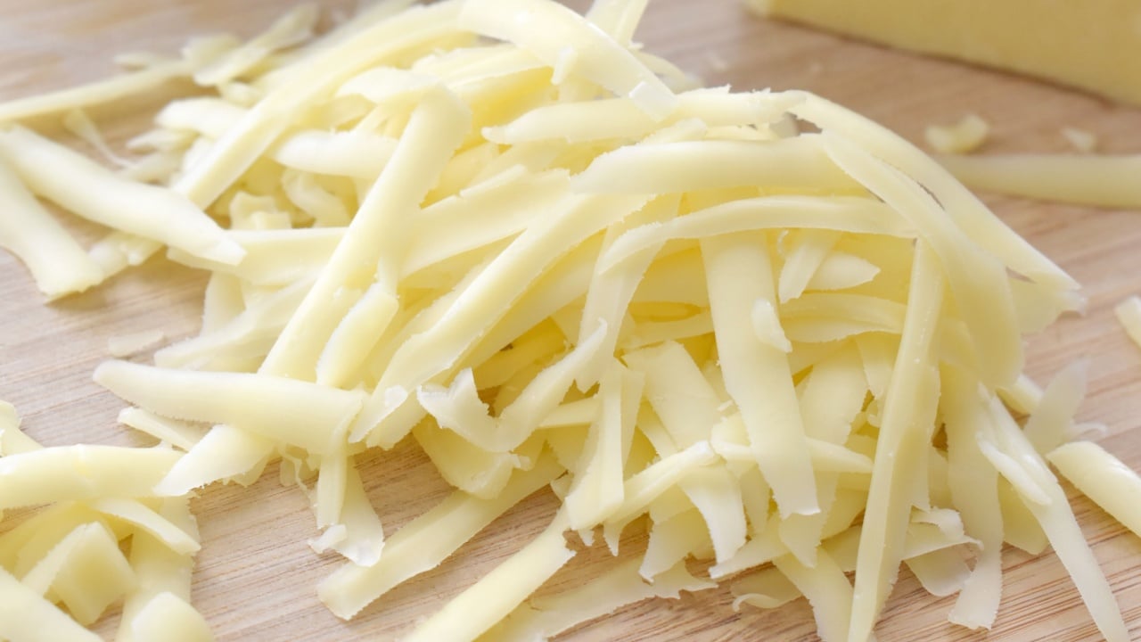 Grated cheese on a bamboo chopping board.
