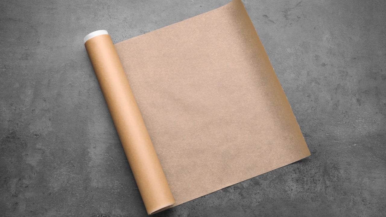 Roll of baking paper on grey table, top view