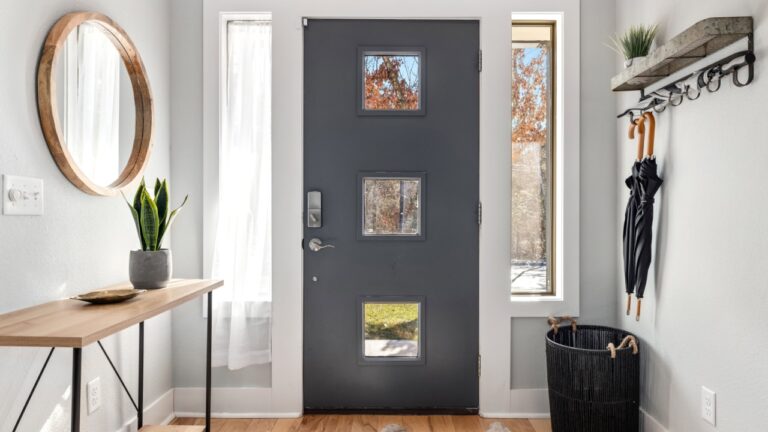 FAYETTEVILLE, UNITED STATES - Nov 16, 2022: The residential entryway of a house with a gray door, hanging umbrellas, and a round mirror