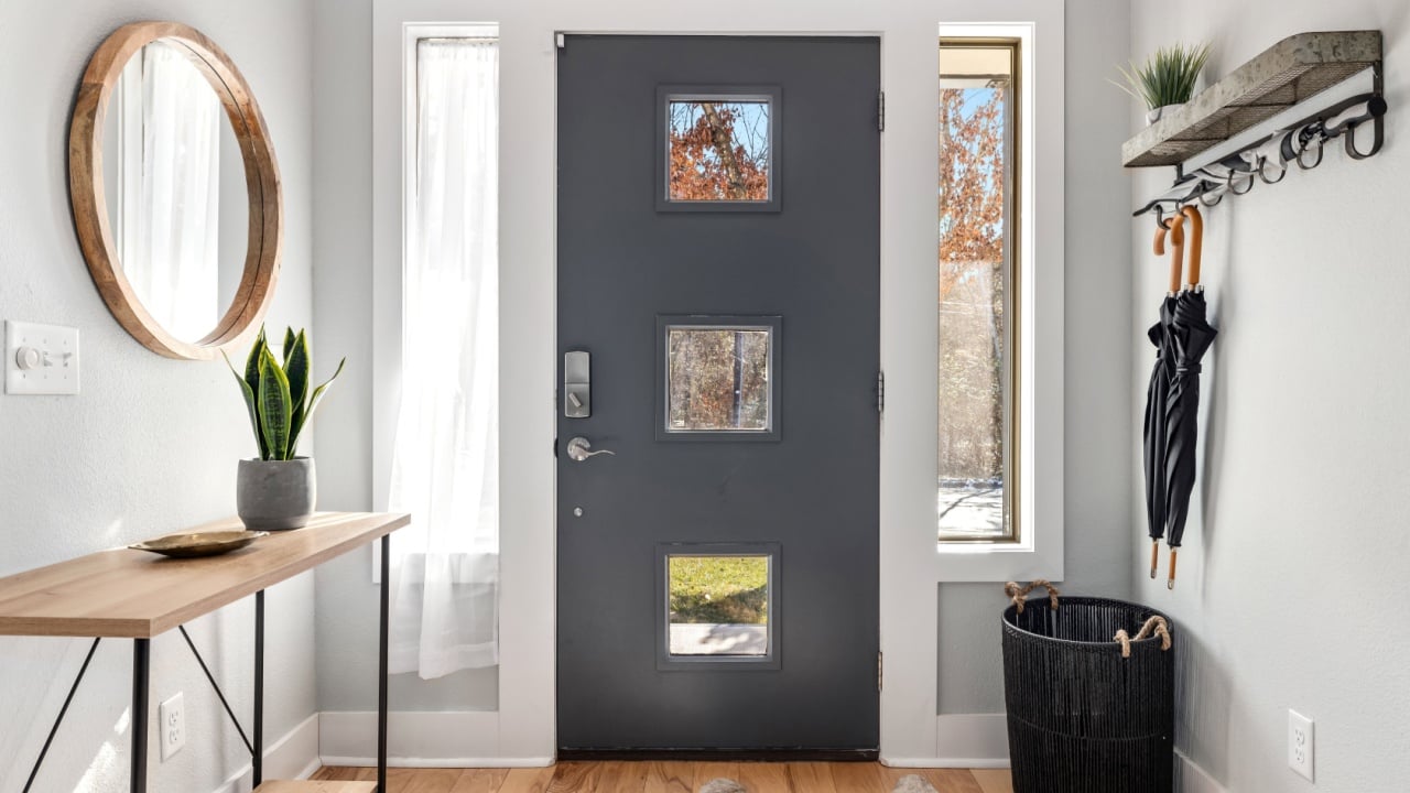 FAYETTEVILLE, UNITED STATES - Nov 16, 2022: The residential entryway of a house with a gray door, hanging umbrellas, and a round mirror