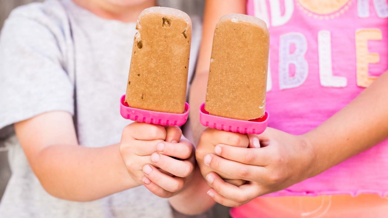 The kids holding homemade tasty frozen pudding pops on the blurred background