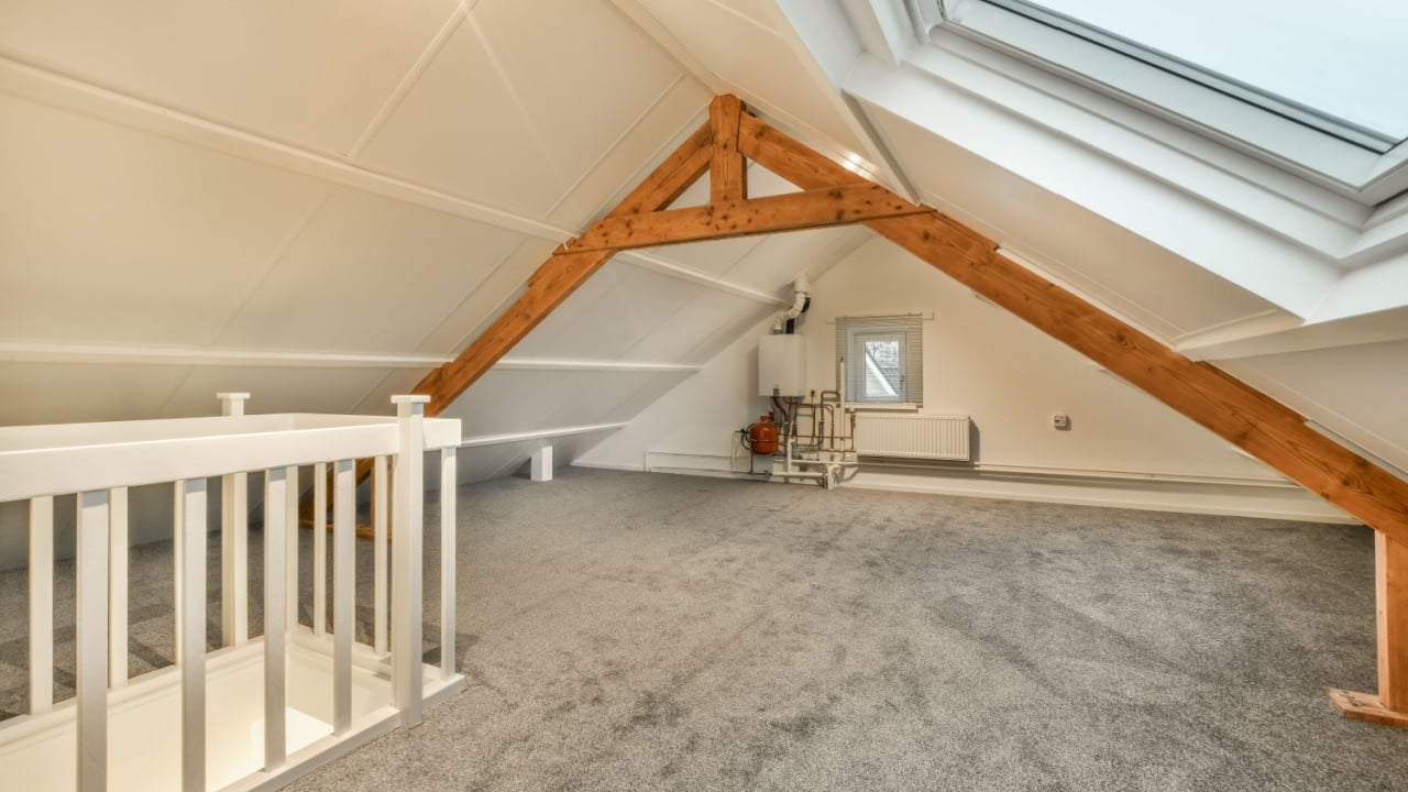 an attic loft with skylights and carpeted flooring in the attic, which has been used as a home office