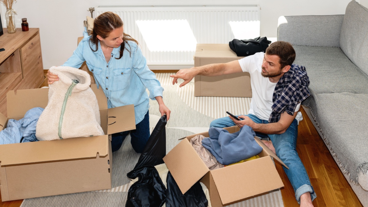 Young married couple packing their clothes for charitable organisation.