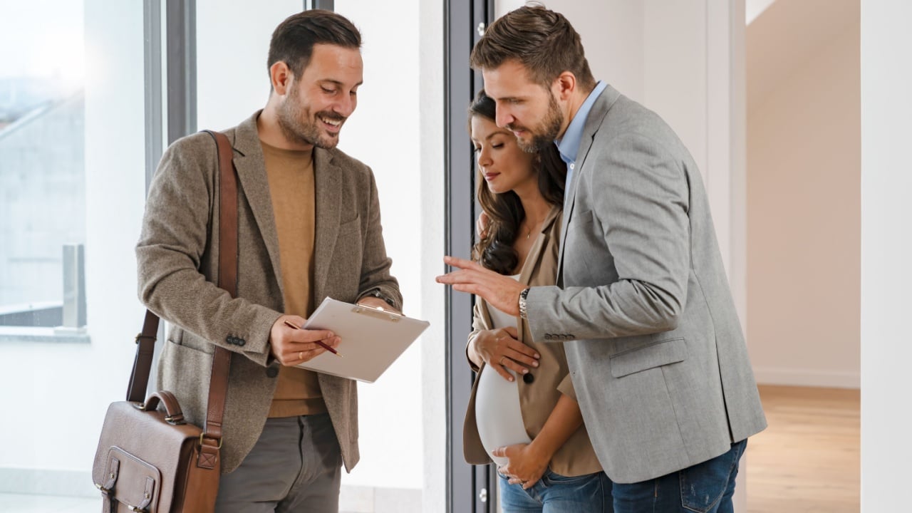 A young couple with a real-estate agent visiting an apartment for sale or for rent. Married couple buying an apartment. Real estate concept.