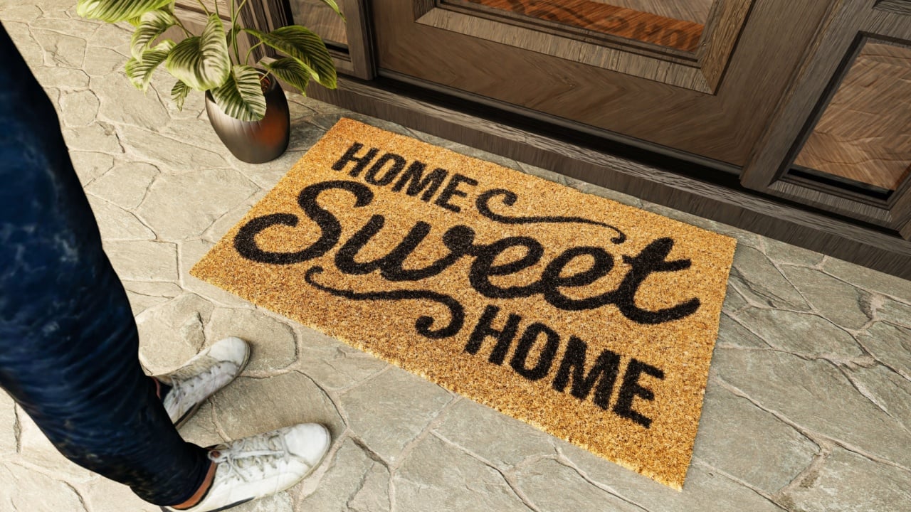 Home Sweet Home doormat and shoes of a man standing on the porch at the front door.