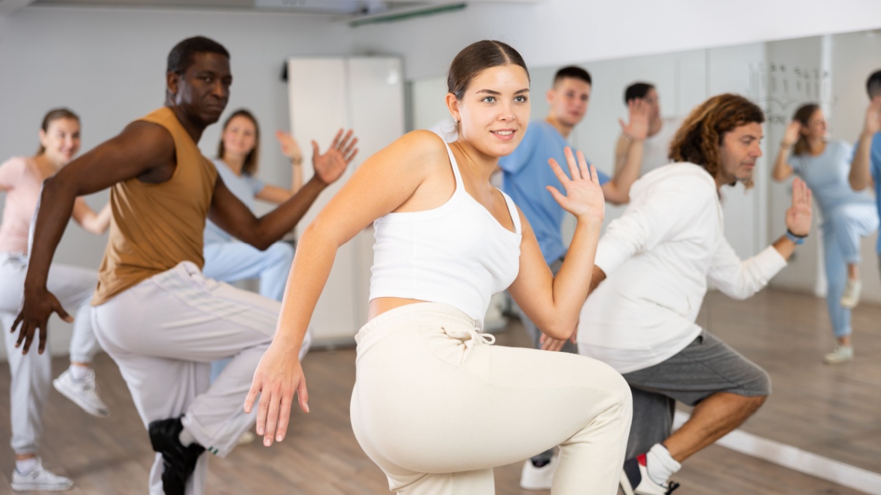 Group of positive dancers repeat dance in dance hall