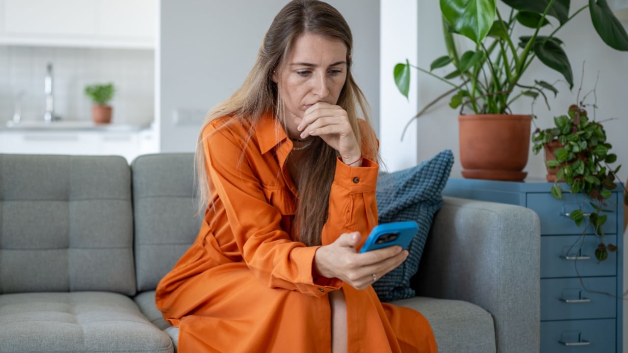 Worried woman holding cellphone, anxiously gazing at screen, awaiting call or message. Upset female read news look with tension of uncertainty on smartphone with bad thoughts in head, loss connection