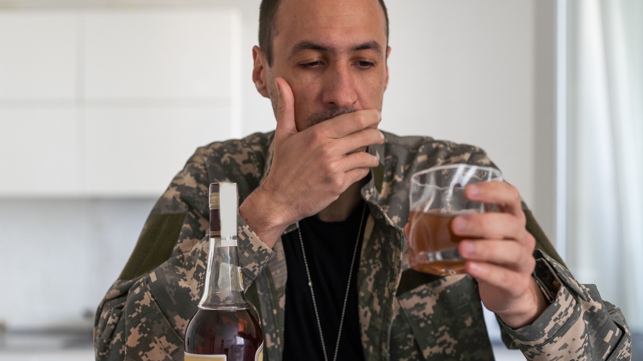  veteran holding bottle of whiskey near face while sitting in wheelchair with closed eyes
