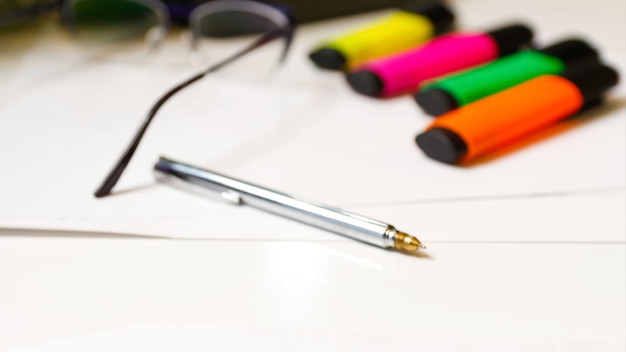Collection of silver pen and colorful markers elegantly arranged on a clean white desk. Quality writing instruments and organizational tools in optimizing productivity. 