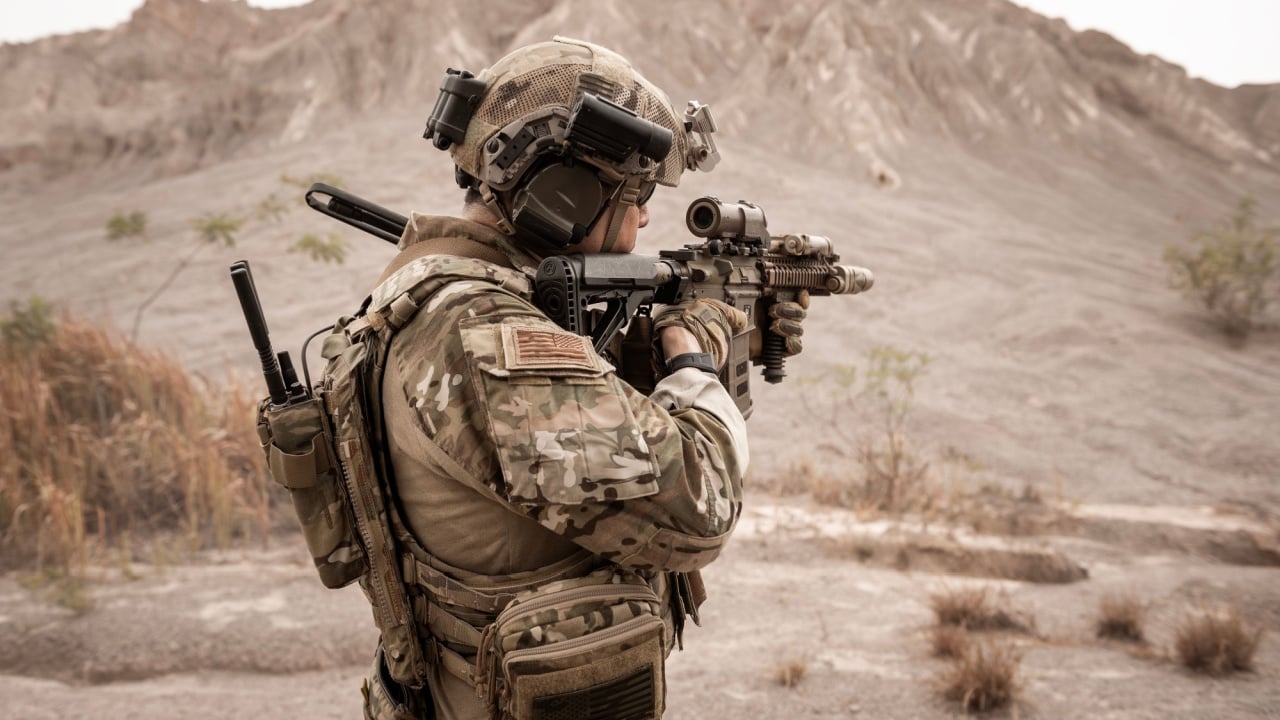 Soldiers in camouflage uniforms aiming with their rifles ready to fire during military operation in the desert , soldiers training in a military operation