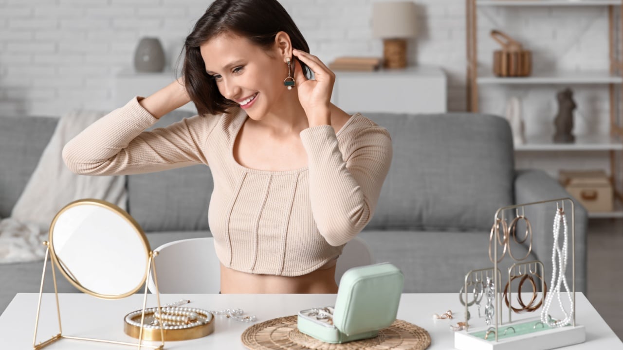 Beautiful young happy woman with stand and storage box of different stylish jewelry at home