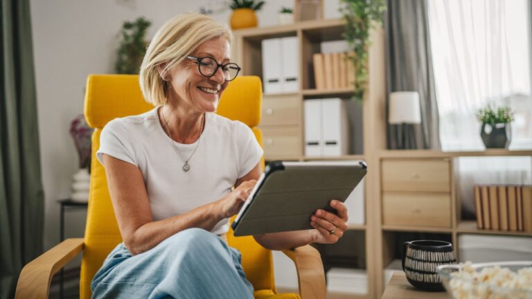 Mature senior woman sit at home and use mobile phone for text message, video call or browse internet